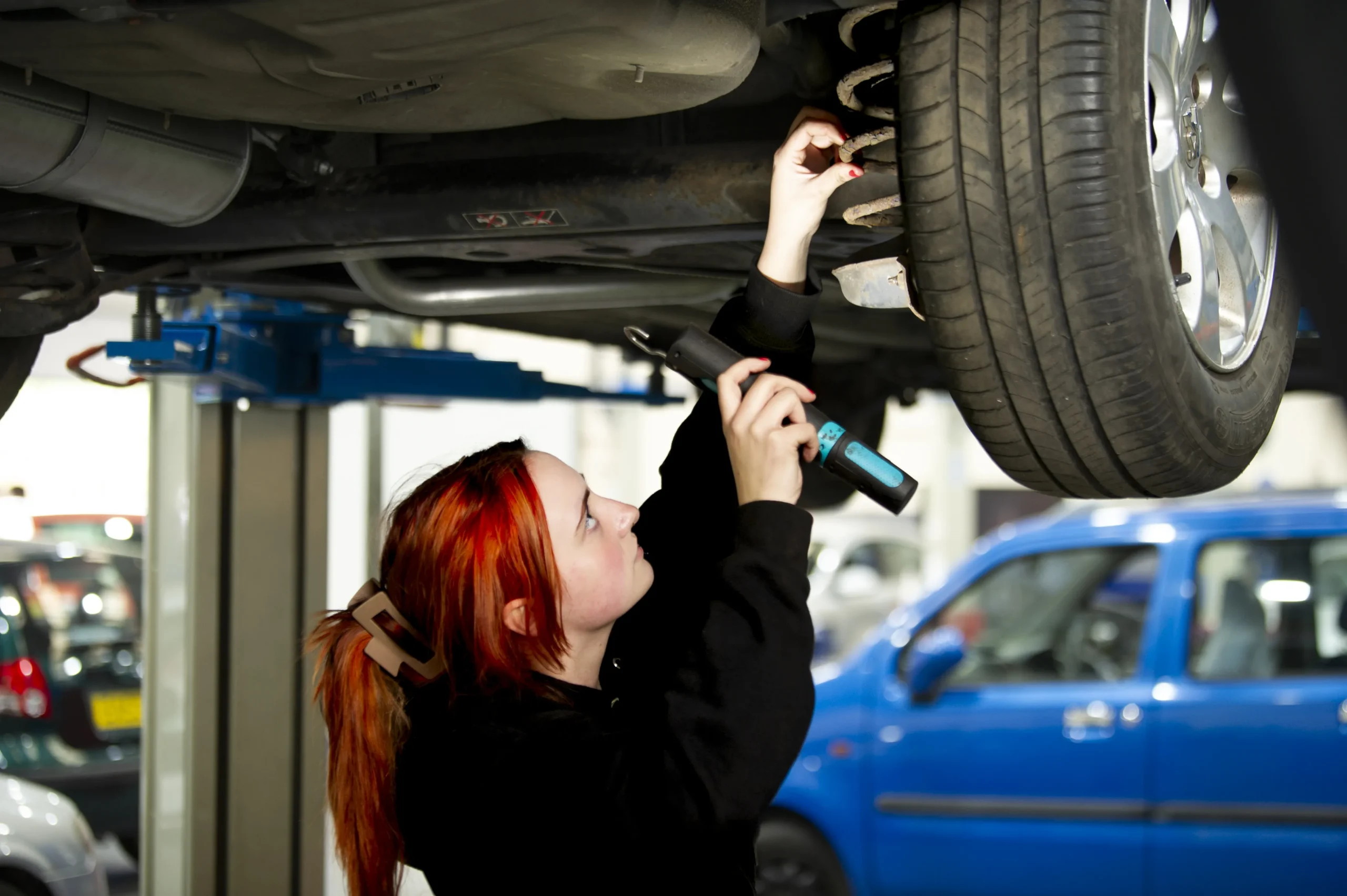Student fixing the bottom of a car