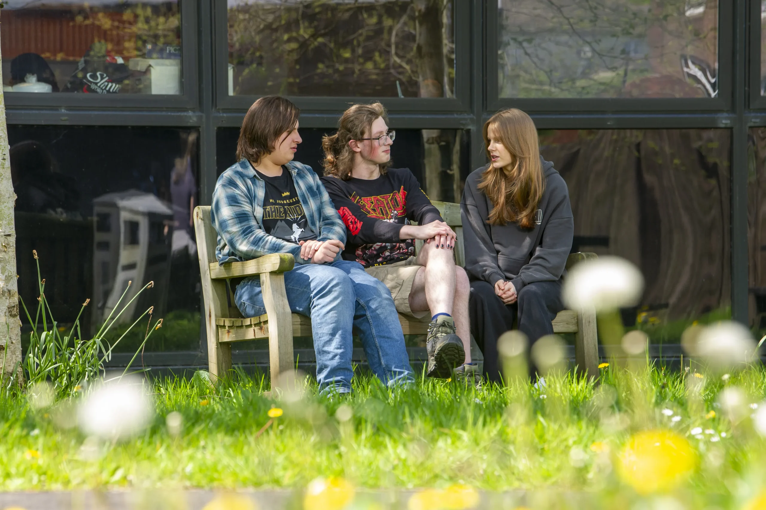 Three students on a bench talking